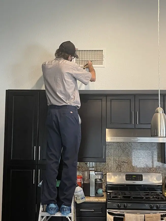 Technician inspecting an air vent during HVAC service in South Fayette